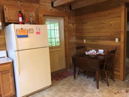 a kitchen and dining room with a refrigerator and a table at Country Road Cabins in Hico