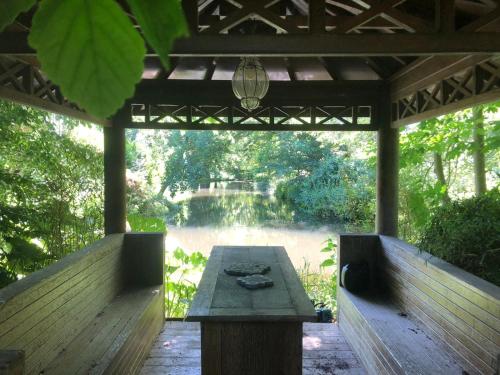 a wooden pergola with a table and a view of a river at 't Koetshuys in Heenvliet