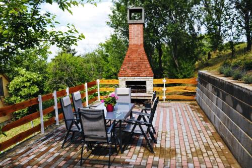 a patio with a table and chairs and a fireplace at Szőlőskert Vendégház in Baj