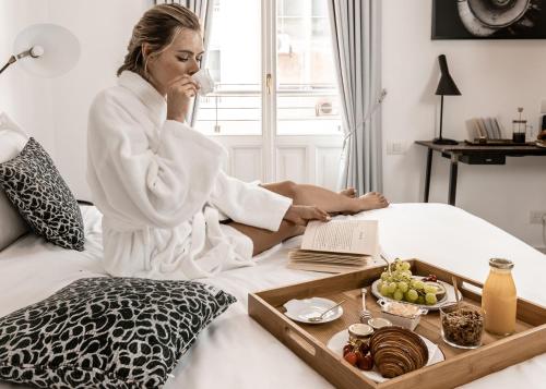 a woman sitting on a bed with a tray of food at Renoma in Tel Aviv