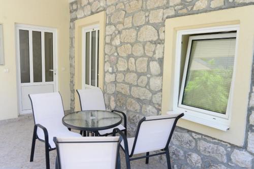 un patio con tavolo, sedie e parete in pietra di Apartments Ivanovic a Kotor (Cattaro)