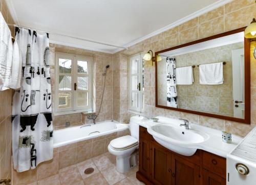 een badkamer met een bad, een wastafel en een toilet bij Villa Antoon in Yírion