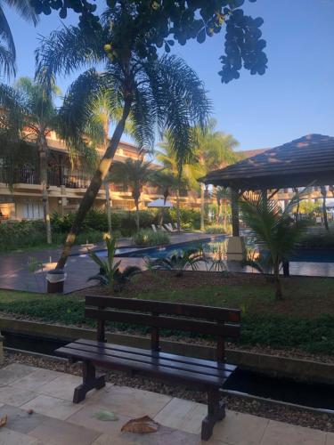 um banco num parque com palmeiras e uma piscina em Residências Garcez, paraíso à beira da praia Enseada, Guarujá no Guarujá