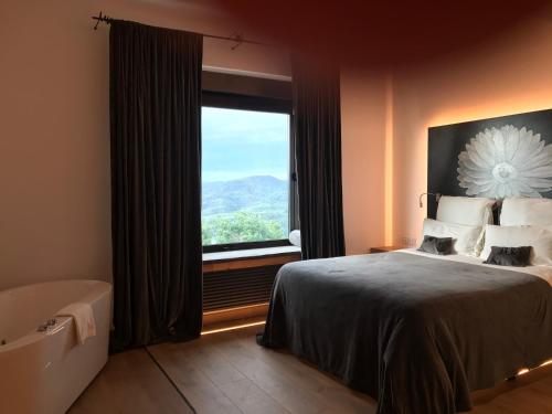 a bedroom with a large window and a bed and a tub at Boutique hotel Urbisol in Calders