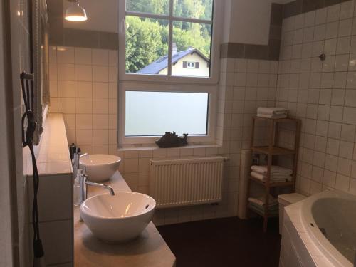 baño con 2 lavabos, bañera y ventana en Auberge Tabarz Zimmerberg en Tabarz