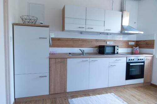 a kitchen with white cabinets and a microwave at Apartmán u Větrníku in Jihlava
