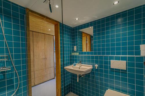 La salle de bains est pourvue de carrelage bleu, d'un lavabo et d'une douche. dans l'établissement Domein De Kleine Mote, à Heuvelland