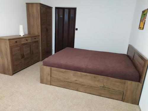 ein Schlafzimmer mit einem Holzbett und einer Kommode in der Unterkunft Apartmán Jan in Břeclav