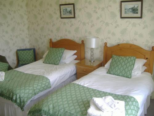 twee bedden met groene en witte lakens in een kamer bij South Moor Farm in Scarborough