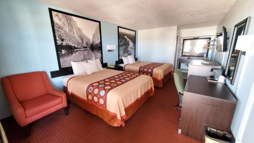 ein Hotelzimmer mit 2 Betten, einem Schreibtisch und einem Stuhl in der Unterkunft Super 8 by Wyndham Van Horn in Van Horn