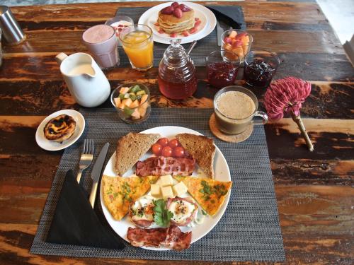 Una mesa cubierta con platos de desayuno y bebidas. en Manta Ray Lodge, en Horta