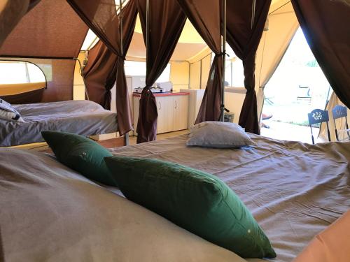 - 2 lits dans une tente avec des oreillers verts dans l'établissement Tente Lodge les Gîtes de l'Odet, à Lanio