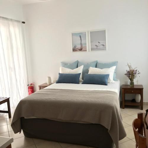 a bedroom with a large bed with blue pillows at Volta Superior Studios in Avlemonas