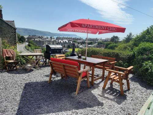 a table with a red umbrella and two chairs at Apartment Chic in Barmouth