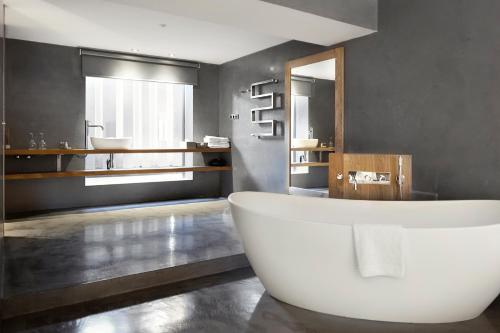 a bathroom with a large tub and a mirror at Hotel Urbisol in Calders