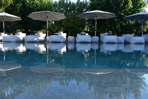 a swimming pool with umbrellas and white chairs at Boutique hotel Urbisol in Calders