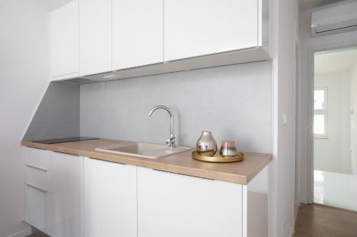 una cocina con armarios blancos y fregadero en IvMaLu Apartments, en Tučepi
