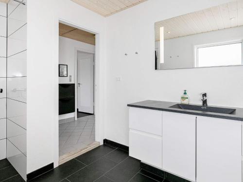 a white kitchen with a sink and a mirror at Holiday home Skagen XXX in Skagen
