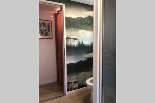 a bathroom with a painting on the wall next to a toilet at Maison la Déco Verte in Braine