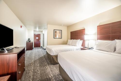 a hotel room with two beds and a flat screen tv at Cobblestone Hotel & Suites - Newport in Newport