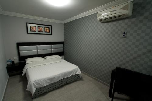 a bedroom with a bed with white sheets and a fan at T Hotel Johor Bahru in Skudai