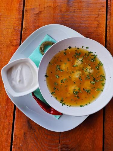 a bowl of soup on a plate on a wooden table at Casa Suzy & Roxy in Arpaşu de Jos