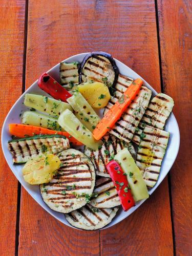 a plate of sandwiches and vegetables on a wooden table at Casa Suzy & Roxy in Arpaşu de Jos