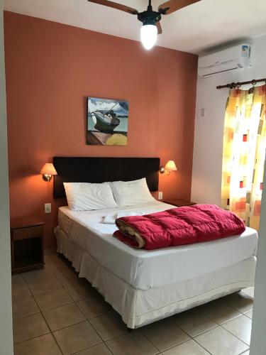 - une chambre avec un grand lit et un mur rouge dans l'établissement Praias Brancas. Boa Vida, à Florianópolis