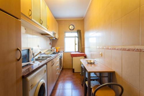 a small kitchen with a table and a sink at Casa de Praia in Costa da Caparica