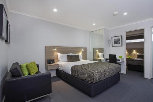 een slaapkamer met een bed, een bank en een stoel bij Hamilton Lonsdale Motel in Hamilton