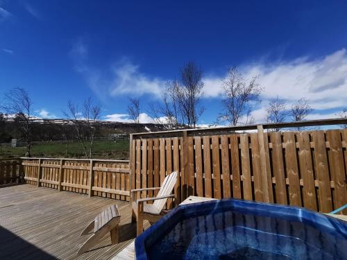 einen Whirlpool auf einer Terrasse neben einem Holzzaun in der Unterkunft Hotel Kjarnalundur- Aurora Dream - Lodges and Rooms in Akureyri