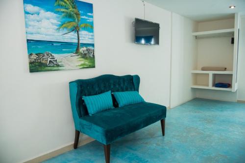 a living room with a blue chair and a painting at Hidalgo Boutique Rooms in Isla Mujeres