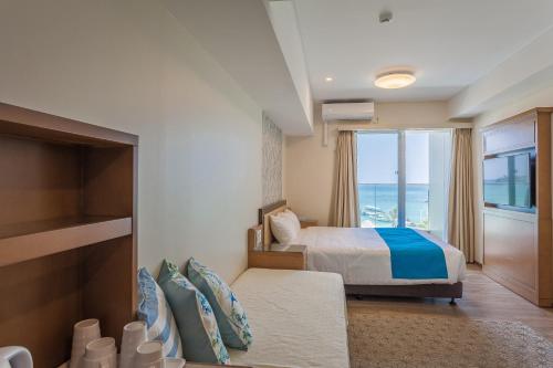 um quarto com uma cama e vista para o oceano em Kariyushi LCH. Resort em Nago