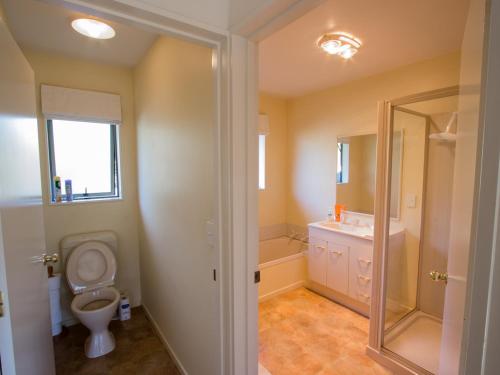a bathroom with a toilet and a sink at Tasman Treat - Marahau Holiday Home in Marahau