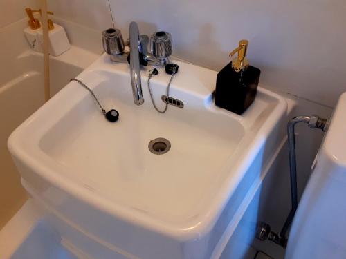 um lavatório branco numa casa de banho com um dispensador de sabão em Guest house Shijo K12 A202 em Quioto