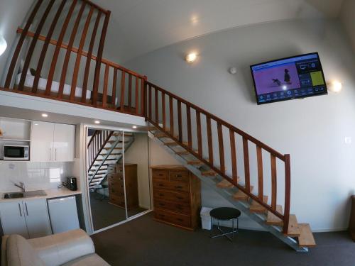 a living room with a staircase with a tv on the wall at Kallangur Motel in Kallangur