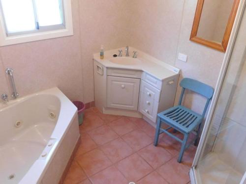 a bathroom with a tub and a sink and a blue chair at Cottage 57 - Topspot Cottages in Jurien Bay