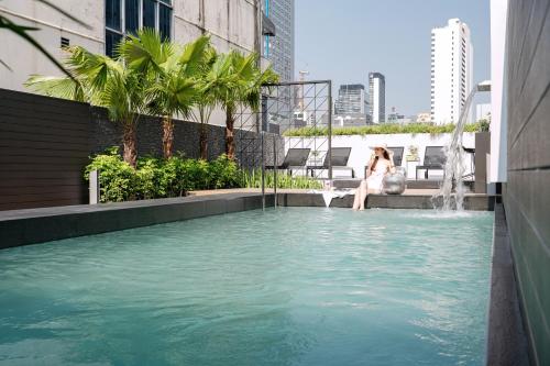 a woman sitting in a pool with a fountain at Citichic Sukhumvit 13 by Compass Hospitality - Newly Renovated in Bangkok