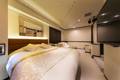 a bedroom with a large bed and a television at i RESORT ARTIA Sensual Gifu (Adult Only) in Ginan