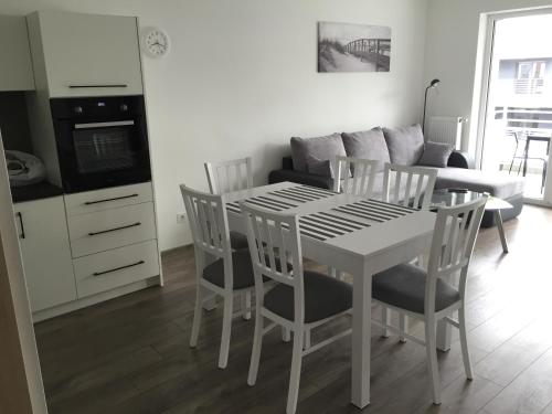 a white dining room table and chairs in a living room at Apartament Baltic Park in Pogorzelica