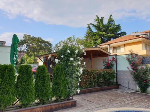 a house with a fence with bushes and flowers at Mirana Family Hotel in Burgas City