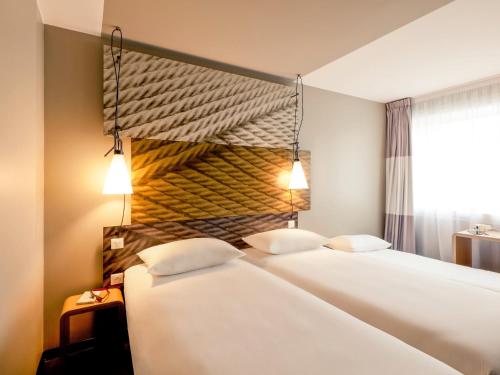 two beds in a hotel room with two lamps at ibis Gent Centrum Opera in Ghent