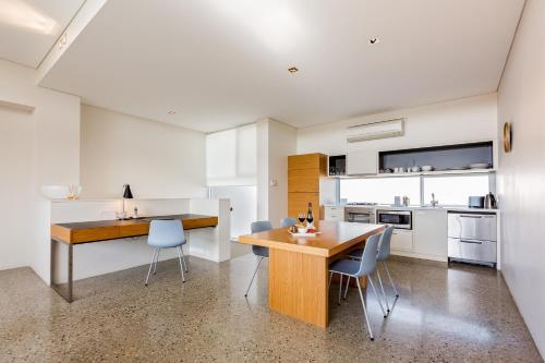 a kitchen with a wooden table and blue chairs at Smiths Beach Resort in Yallingup
