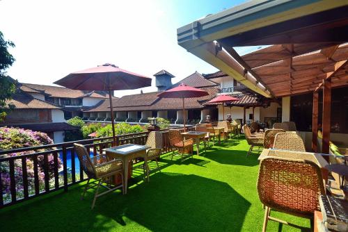an outdoor patio with tables and chairs and umbrellas at Ari Putri Hotel in Sanur