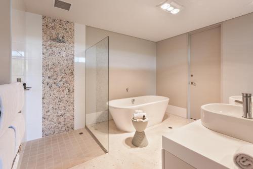 a white bathroom with a tub and a sink at Smiths Beach Resort in Yallingup