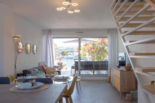 a living room with a table and a staircase at Superbe Marina Rénovée à Neuf en face de la Plage! in Le Grau-du-Roi