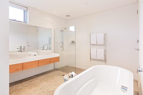 a white bathroom with a tub and a sink at Smiths Beach Resort in Yallingup