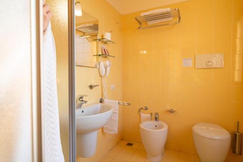 a yellow bathroom with a sink and a toilet at Hotel Mirandola in Mirandola