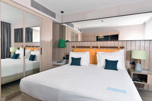 a bedroom with a large white bed with blue pillows at Royal Garden by Isrotel Collection in Eilat