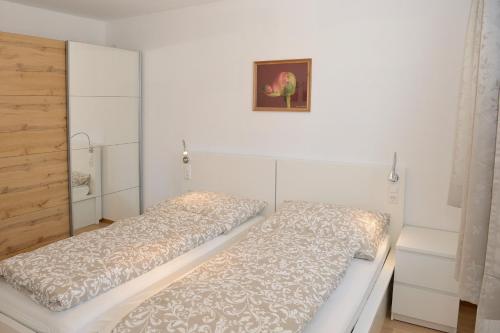 Habitación blanca con 2 camas y una foto en la pared. en Apartment Blaser, en Mühlbachl